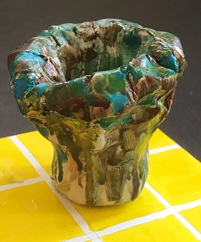 photo of green pinch pot on a table top decorated with yellow squares