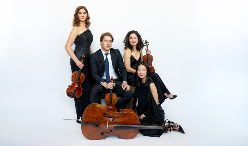 photo of quartet musicians with their instruments seated and standing against a bluish white gradient backdrop