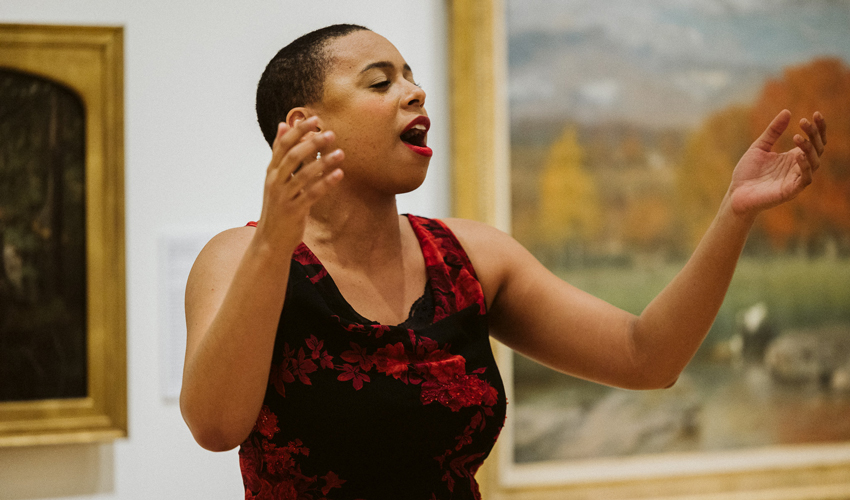 photo of opera singer in red dress singing in museum gallery