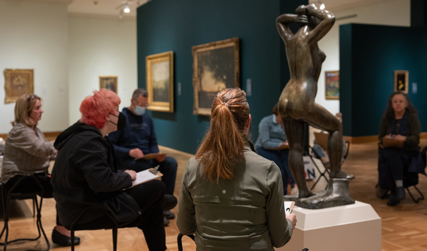 photo of people in a gallery sketching a sculpture of a person