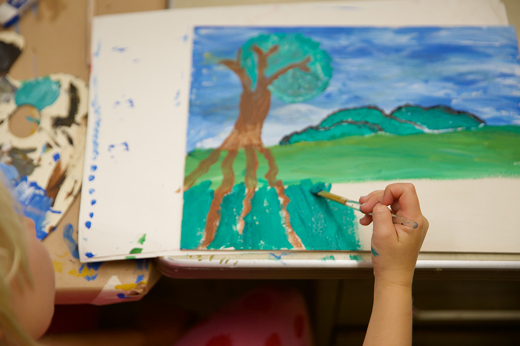 photo of child painting a landscape on paper