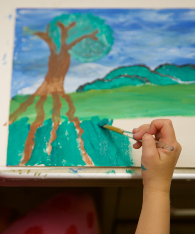 photo of child painting a landscape