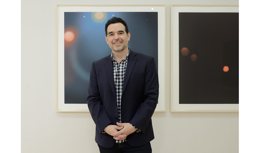 photo of the artist in front of two works on paper featuring celestial objects