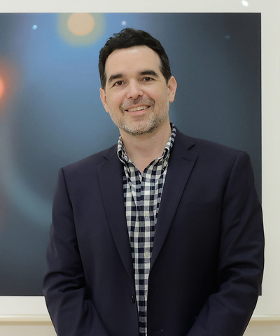 photo of the artist in front of two works on paper featuring celestial objects