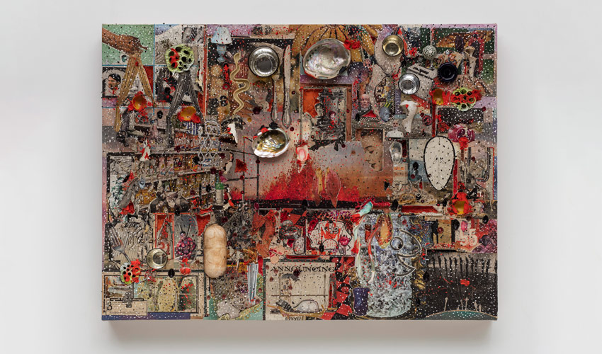 photo of abstract work hanging on a light gray wall, consisting of a heavily worked surface with various objects and color palette of warm tones