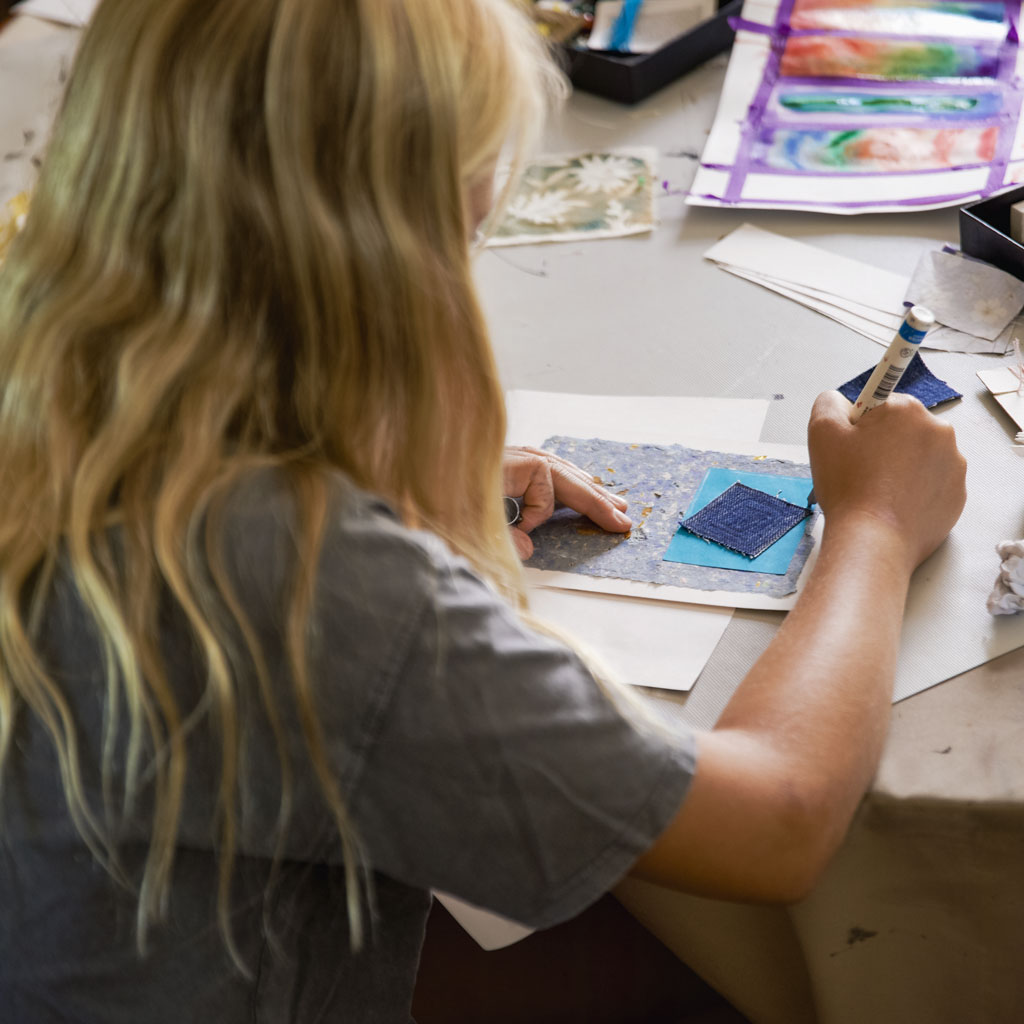 photo of young kid with long blonde hair crafting at a table