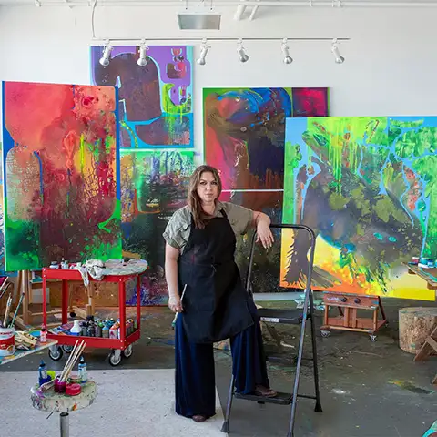 Artist Vian sora standing in front of several of her paintings