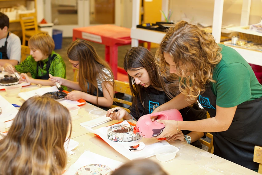 photo of a teacher surrounded by children crafting at a table