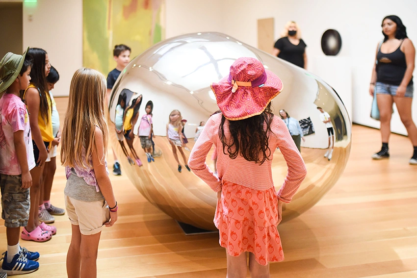 photo of kids in a gallery standing around a reflective silver orb