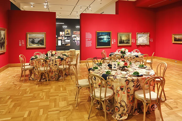 wide shot of a gallery filled with tables set for dinner