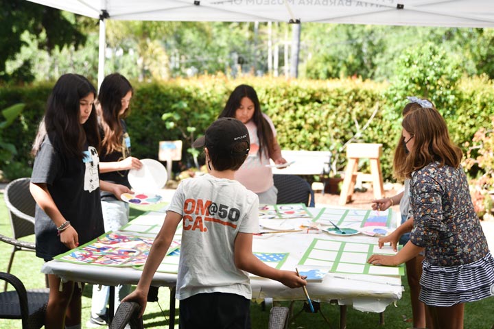 photo of kids crafting at a table under a tent outside on a sunny day