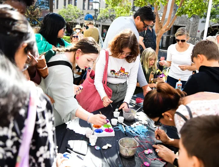 photo of group of people of all ages crafting on a table outside