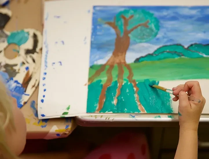 photo of child painting a landscape