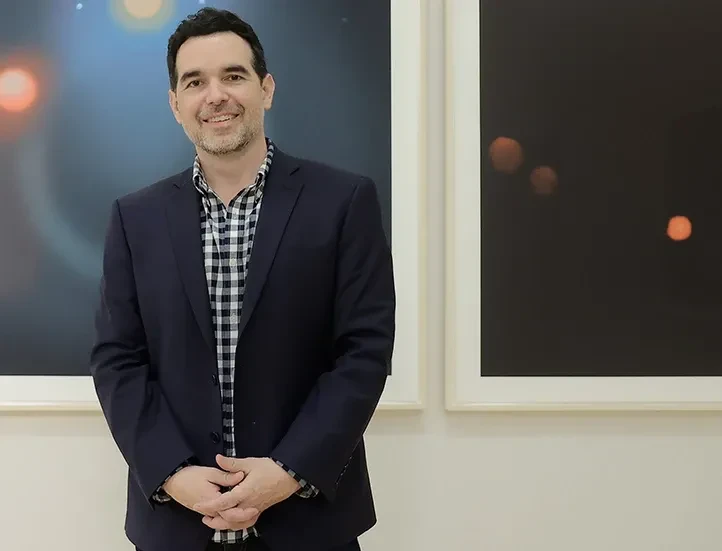 photo of the artist in front of two works on paper featuring celestial objects