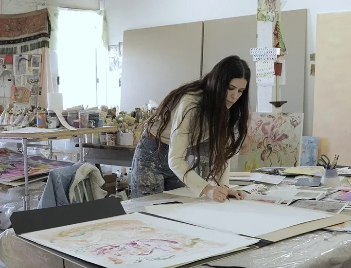 photo of the artist working in her studio, bent over a table drawing