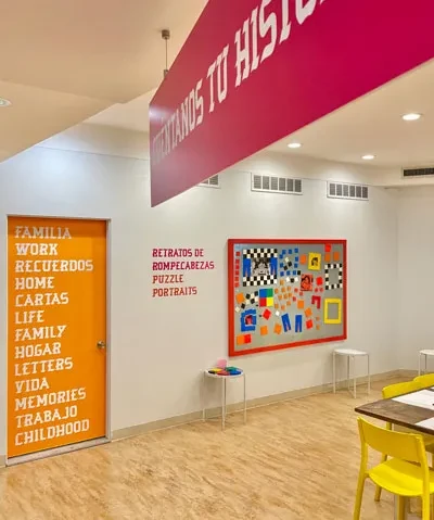 photo of interior of learning center featuring various text and decoration including orange door with words in english and spanish, a work table, and cork board for crafts