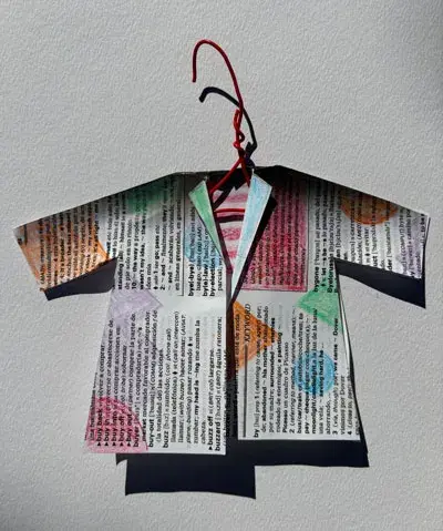 photo of tiny coat made out of newsprint covered in colored shapes on a red hanger