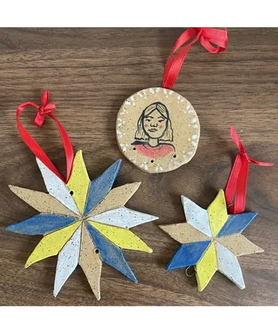 photo of workshop example showing three ceramic hanging crafts, two in a star shape and a round one with a face on it