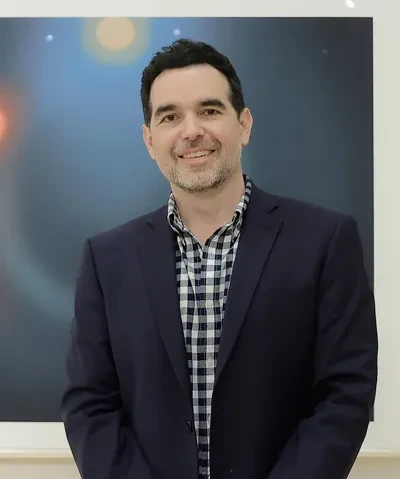 photo of the artist in front of two works on paper featuring celestial objects