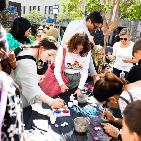 photo of group of people of all ages crafting on a table outside