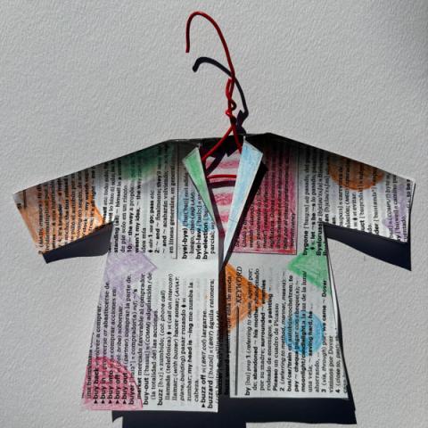 photo of tiny coat made out of newsprint covered in colored shapes on a red hanger