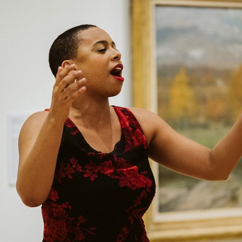 photo of opera singer in red dress singing in museum gallery