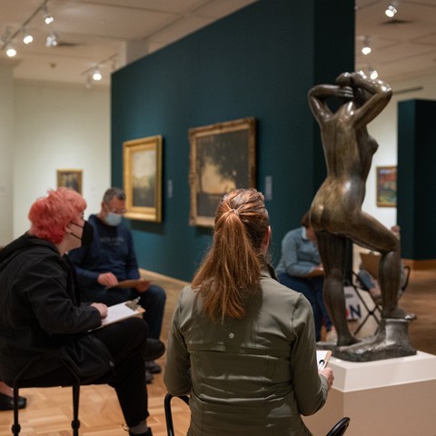 photo of people in a gallery sketching a sculpture of a person