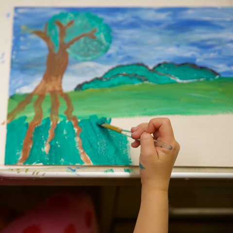 photo of child painting a landscape