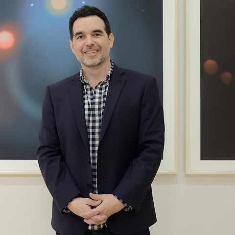 photo of the artist in front of two works on paper featuring celestial objects