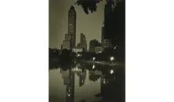 Photo of Central Park at night with a reflection of buildings in the background in the water in the foreground