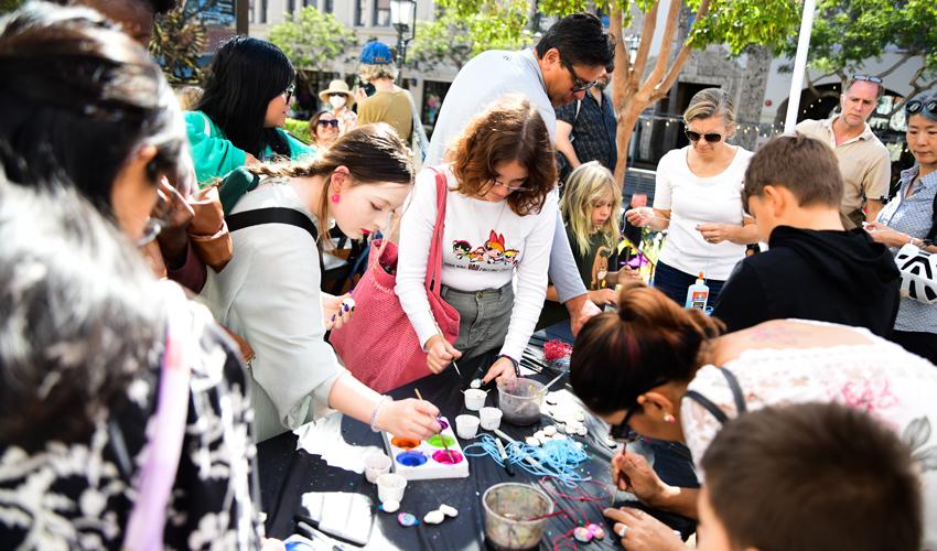 photo of group of people of all ages crafting on a table outside