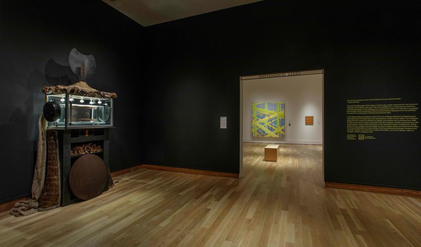 Photograph of Museum interior with a sculpture in the foreground and two paintings in the background