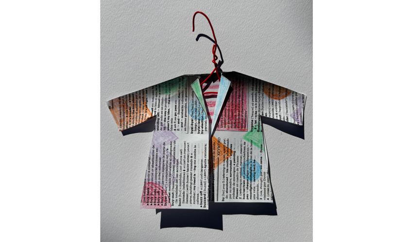 photo of tiny coat made out of newsprint covered in colored shapes on a red hanger