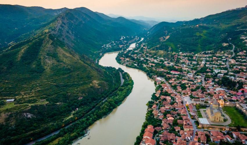 Aerial view of streets of Mtskheta village in Georgia with Svetitskhoveli Cathedral fortress along Mtkvari river